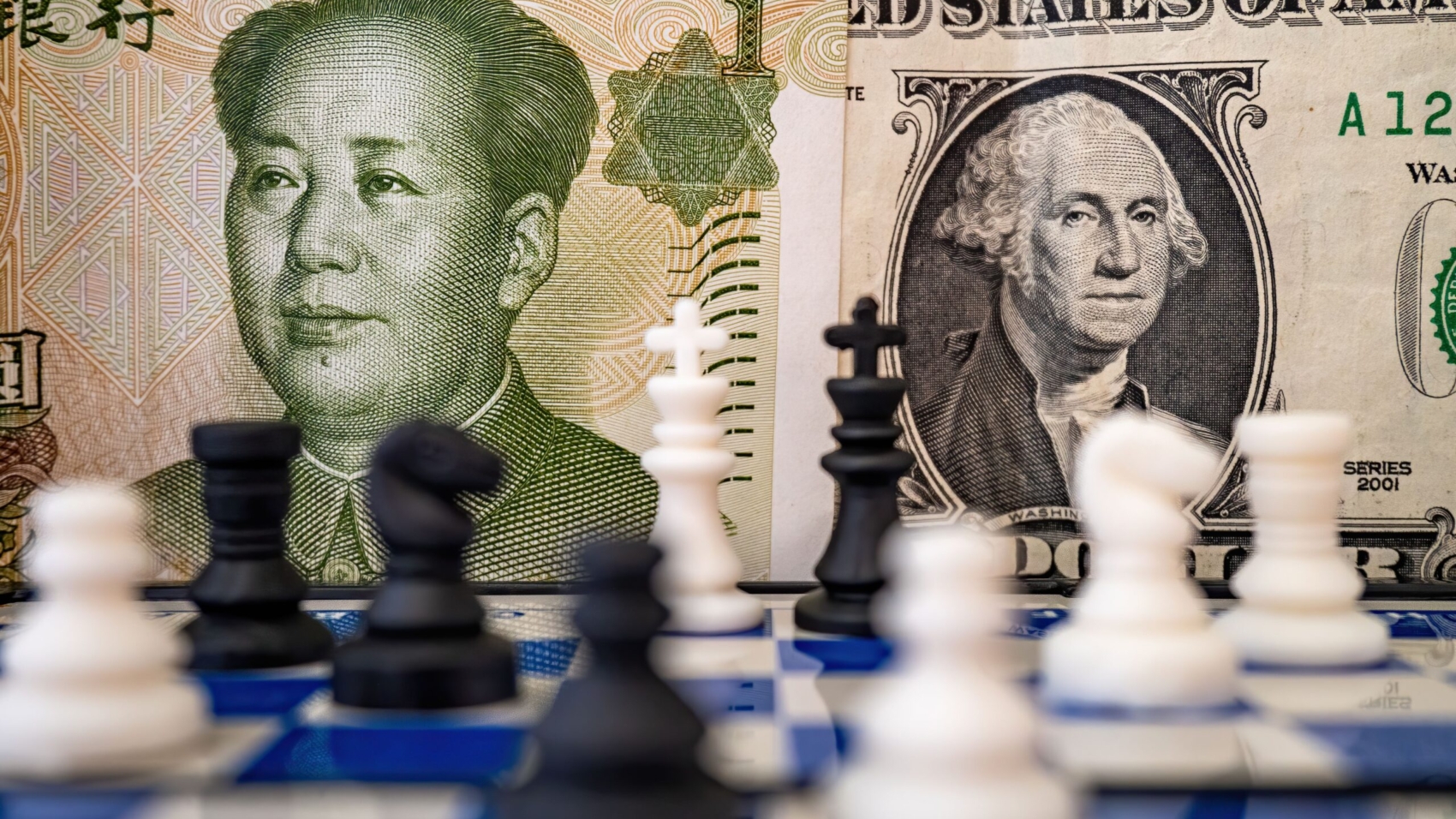 A close-up of a chessboard with a US dollar and Chinese yuan placed on it