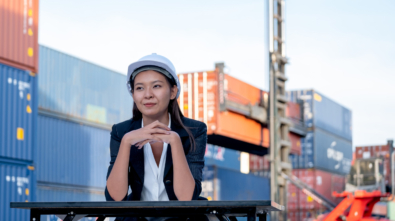 Portrait of engineer worker of factory technician with Chinese woman style sit in front of cargo container crane in workplace area. Concept of good support best successful for industrial business.