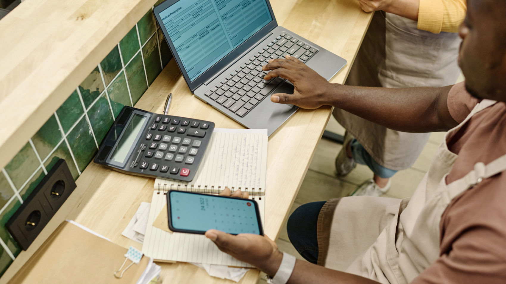High angle view of colleagues working with finance in team using laptop at table in supermarket
