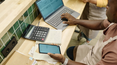 High angle view of colleagues working with finance in team using laptop at table in supermarket