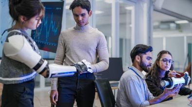 A robotics team develops a new bionic limb, inspecting the prototype while analyzing real-time performance data. A concept for digital twins, agile R&D, and mechatronics innovation.