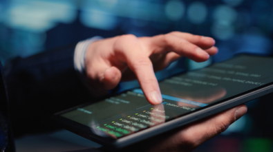 Male system administrator inspecting big data on tablet, working in modern data center. Infrastructure specialist inspecting server rack systems, artificial intelligence. Handheld shot. Close up.
